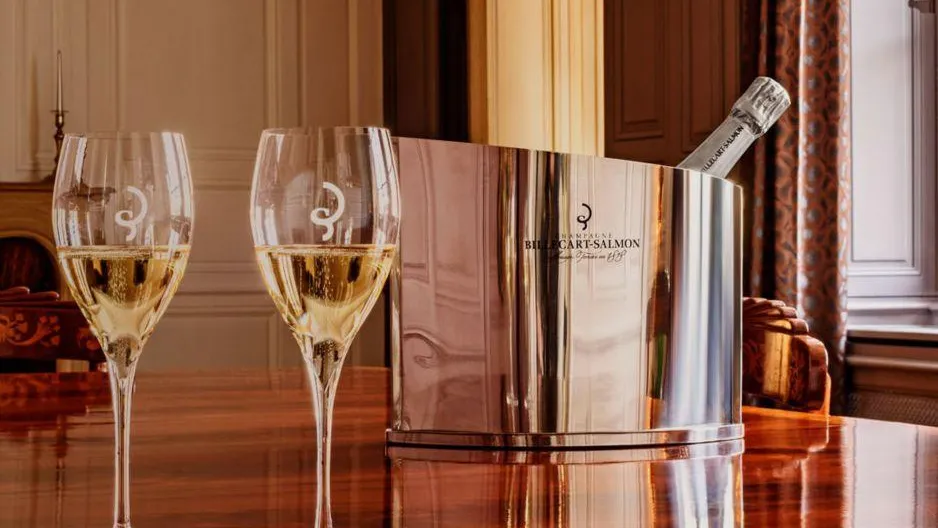 Deux verres à vin remplis de vin blanc posés sur une table en bois à côté d'un seau à champagne contenant une bouteille de champagne