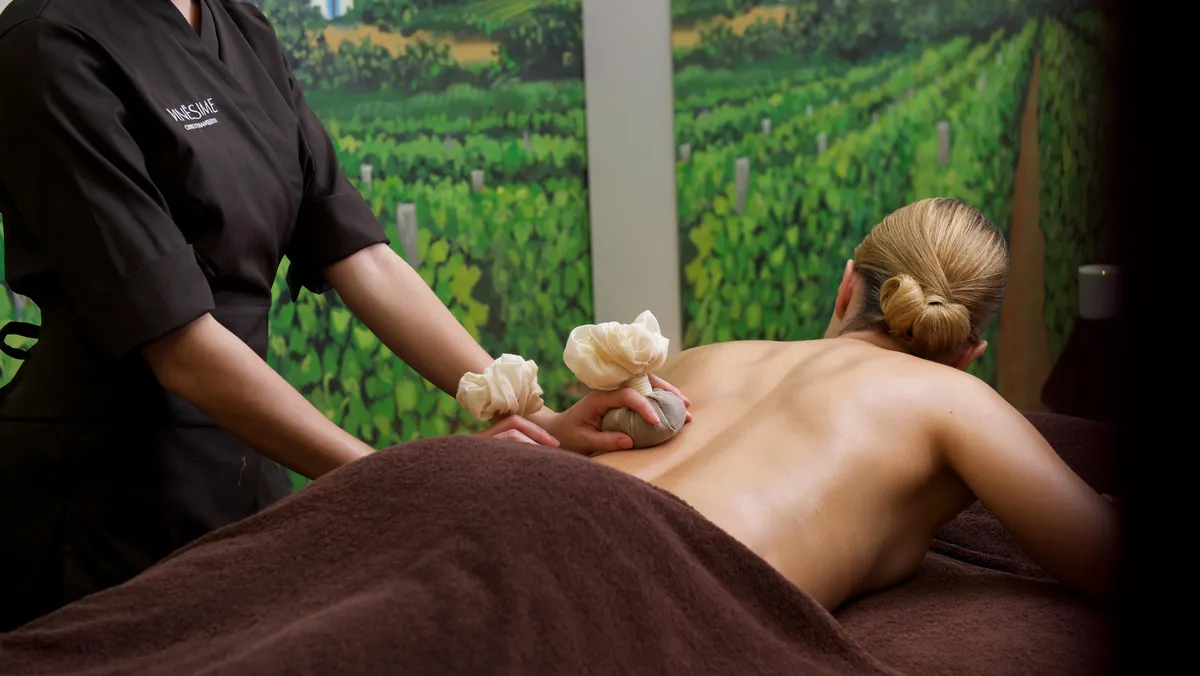Une personne reçoit un massage avec des pierres chaudes par un professionnel dans un cadre relaxant
