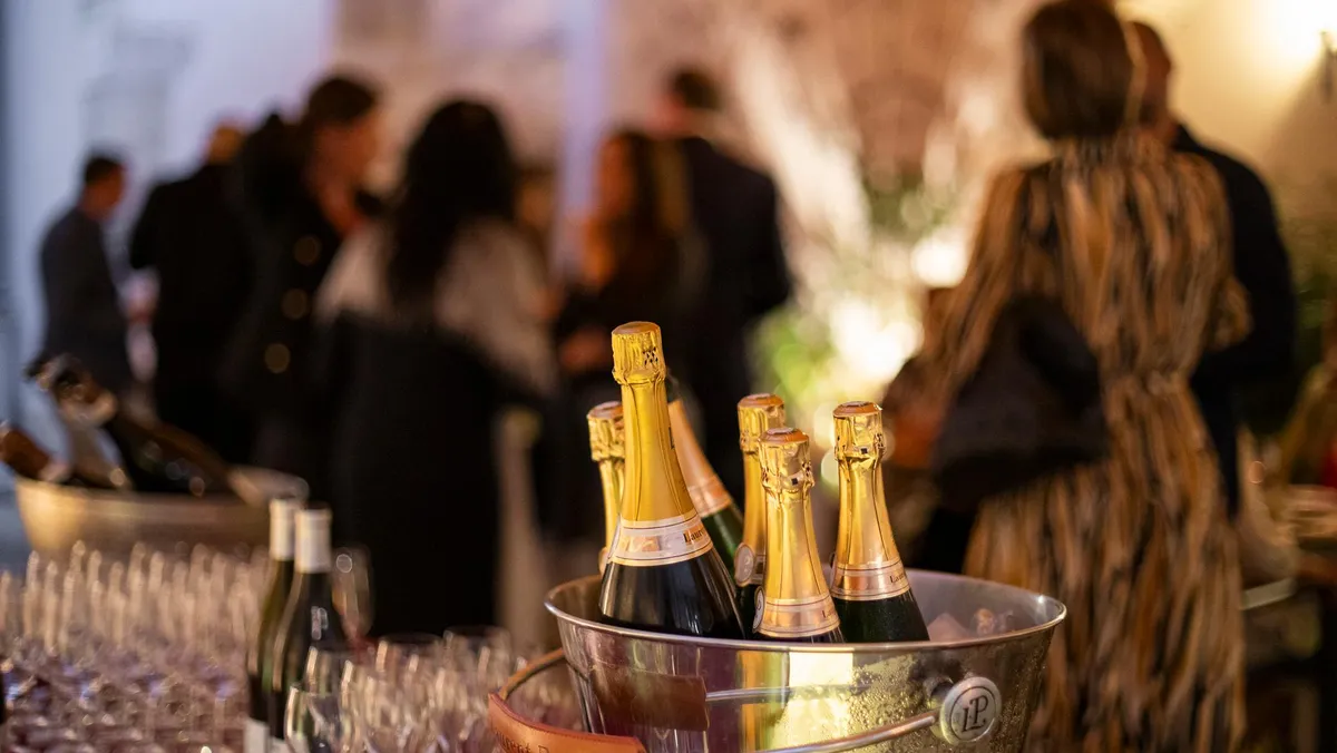 Bouteilles de champagne dans un seau à glace sur une table avec des verres, en arrière-plan des personnes floues en conversation
