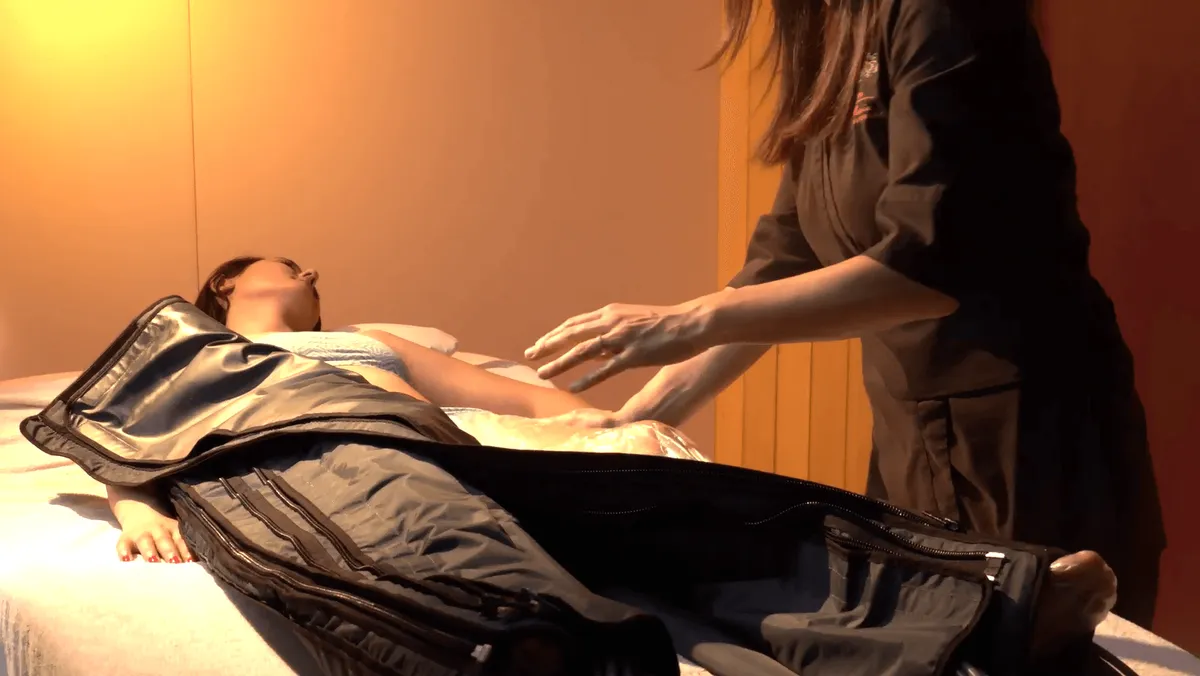 Une personne allongée sur une table reçoit un massage d'une autre personne debout à ses côtés