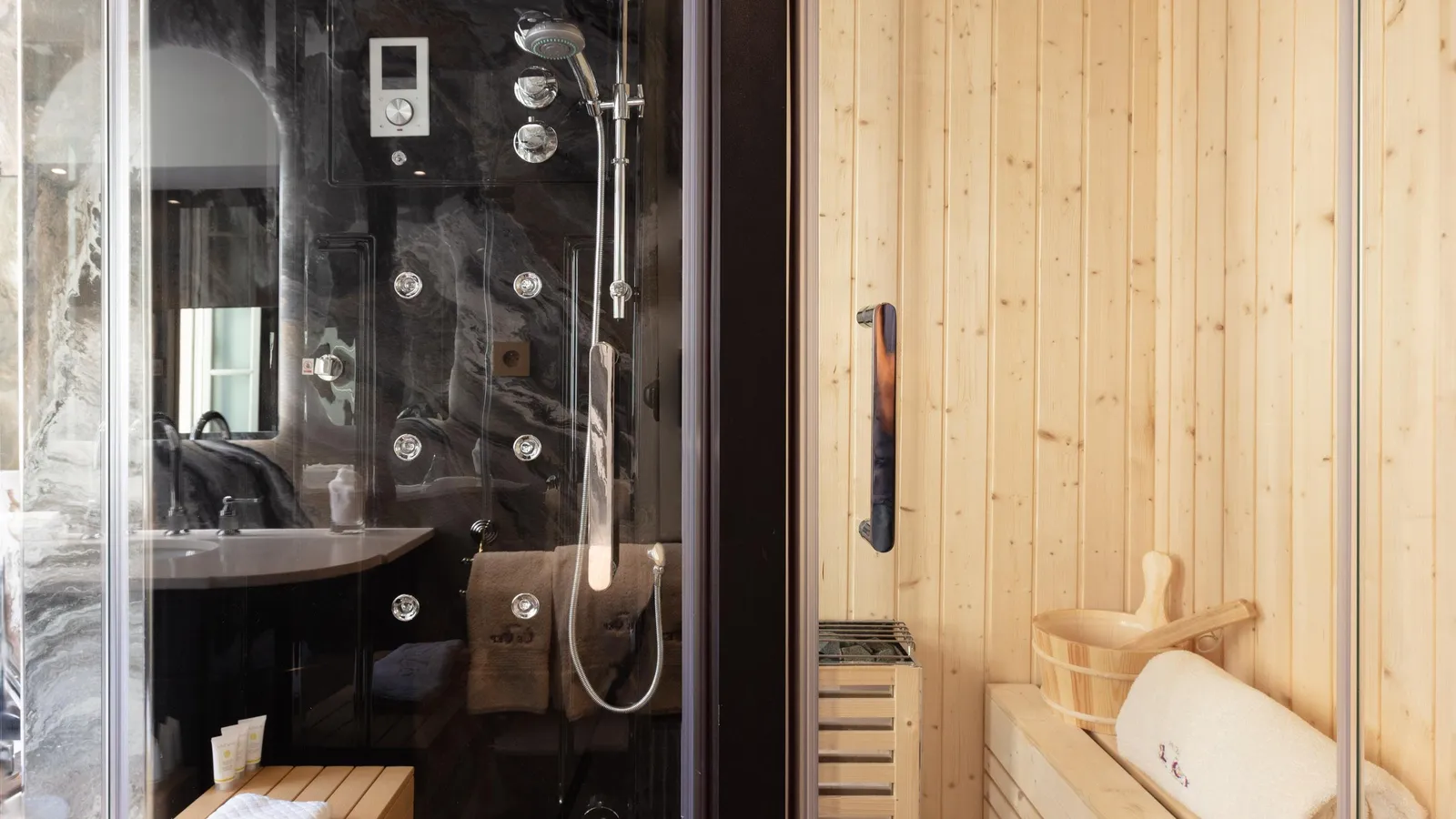 Douche à effet pluie avec plusieurs buses et sauna en bois avec bancs et serviettes
