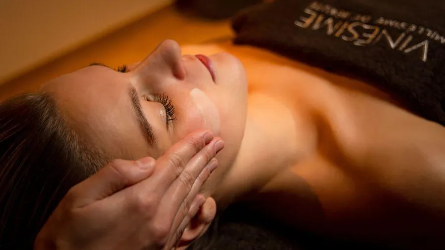 Une personne allongée reçoit un massage facial dans un cadre de spa