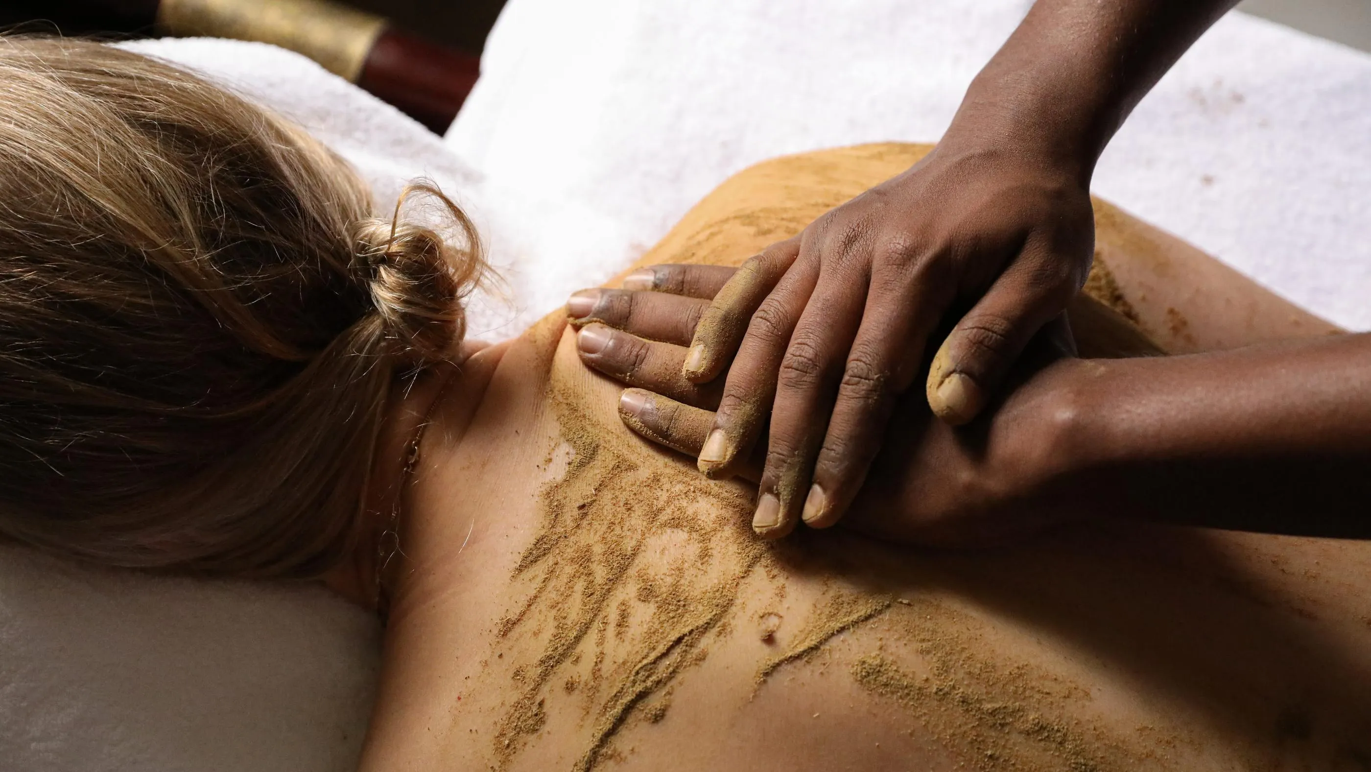 A person receives a massage using powder on the back.