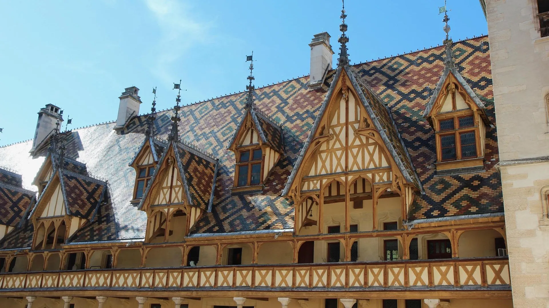 Un bâtiment historique avec une façade en colombages et un toit en ardoise aux multiples pignons et lucarnes