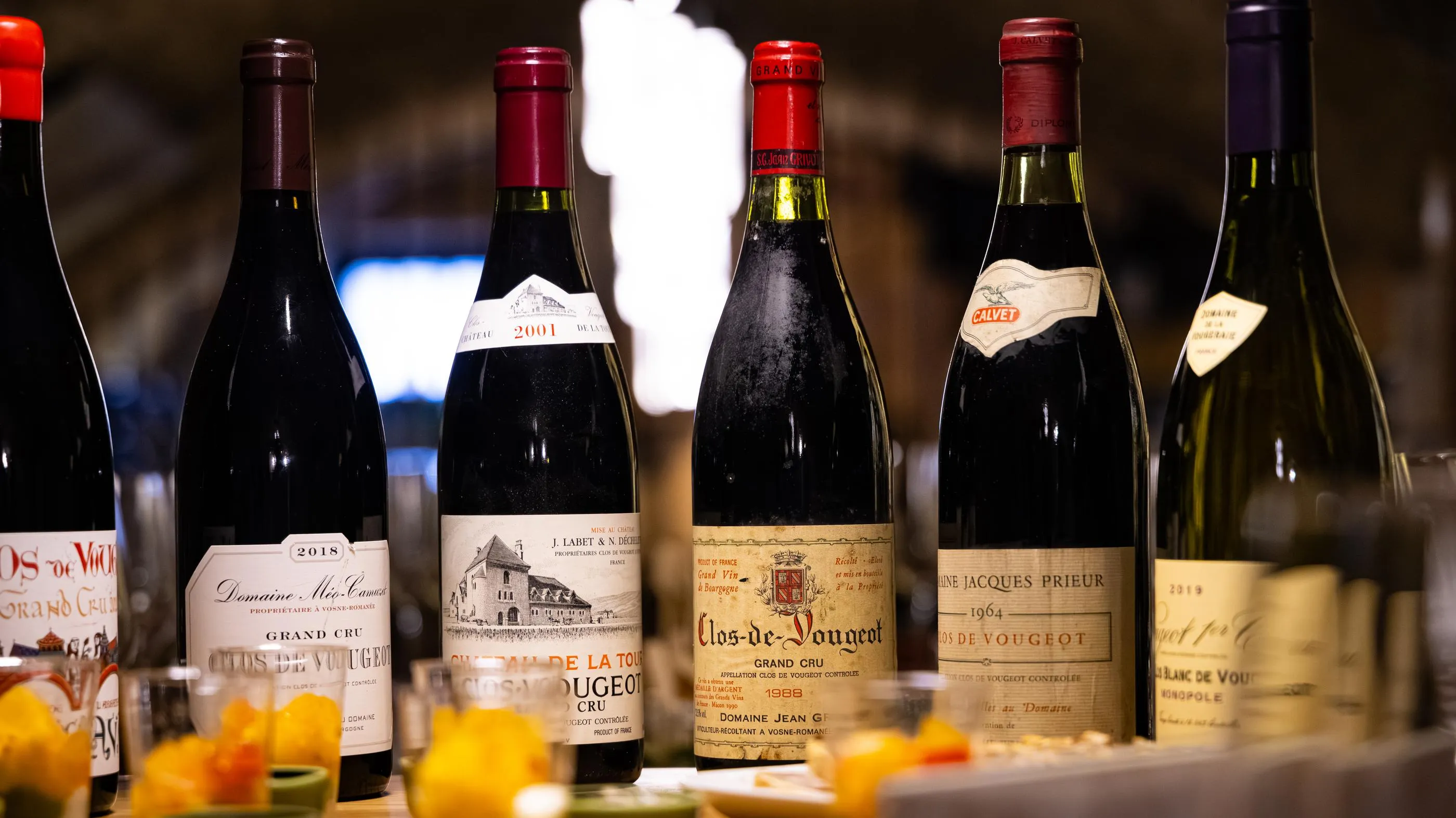 Several wine bottles with detailed labels are lined up on a table decorated with flowers.