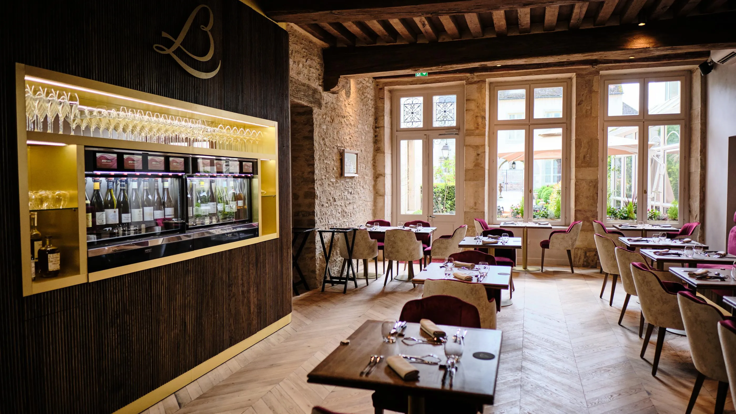 Restaurant with set tables, lit wine bar, and large windows letting in natural light.