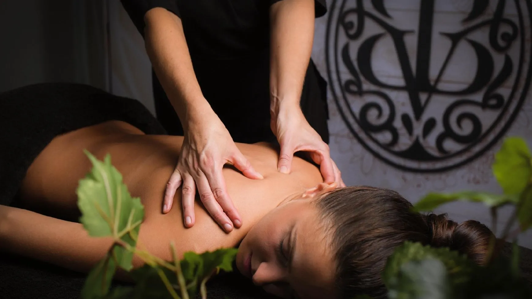 Une personne reçoit un massage dans le dos, allongée sur le ventre, avec des mains appliquant une pression sur sa peau