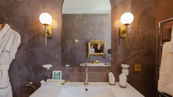 Elegant bathroom with white sink, gold mirror, towels, and toiletries