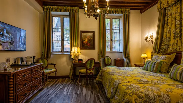 Chambre avec lit à baldaquin, deux fenêtres, un bureau, des chandeliers et une télévision