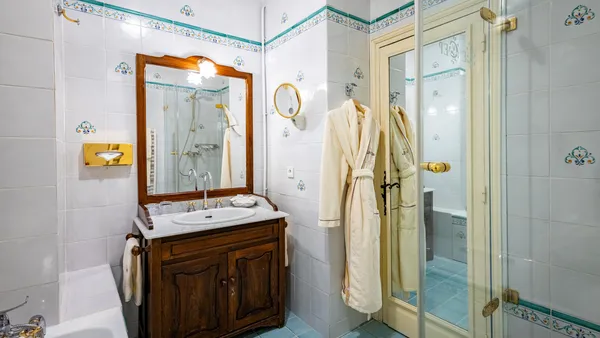 Bathroom with wooden sink, mirror, glass shower, and hanging robes