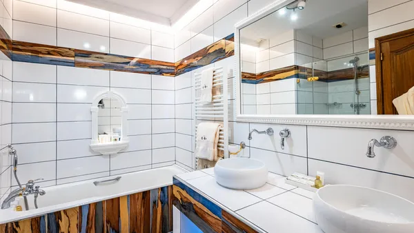 Salle de bain moderne avec lavabo, miroir, étagère chauffante et douche, murs carrelés avec motifs en bois et bleu