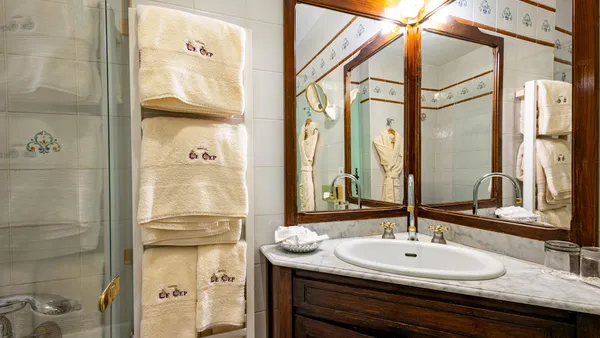 Bathroom with marble sink, wooden-framed mirror, and towels stacked on a towel rack.