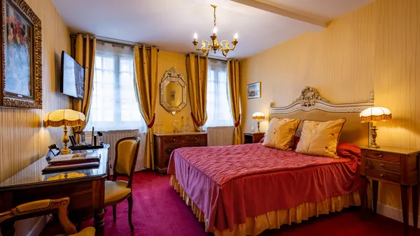 Elegant room with a four-poster bed, wooden furniture, bedside lamps, and yellow curtains in front of a window.