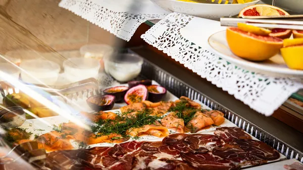 Assiettes de charcuterie, de poisson fumé et de fruits exotiques disposées sur une table avec des serviettes en dentelle