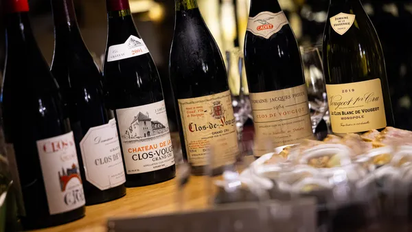 Plusieurs bouteilles de vin avec des étiquettes différentes posées sur une table en bois à côté d'un plat de fromage