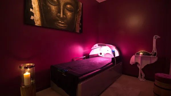 Salle de massage avec un lit de traitement, des bougies allumées, une sculpture d'oiseau et une image de Bouddha au mur