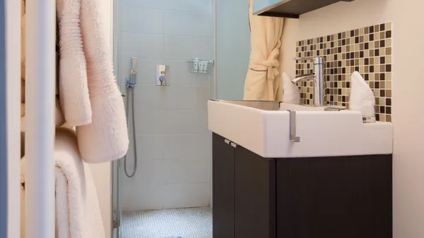 Modern bathroom with rain shower, sink, hanging towels, and storage shelves