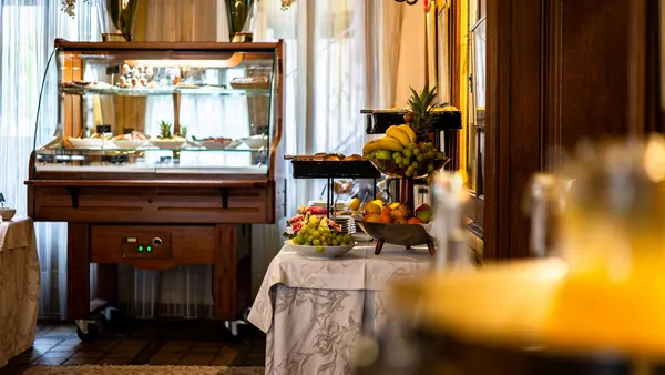 Breakfast buffet with fresh fruit and pastries in a display case, lit by candles