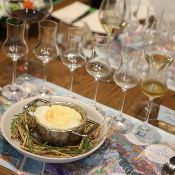 A table with several wine glasses and a dish containing a culinary preparation surrounded by fine herbs
