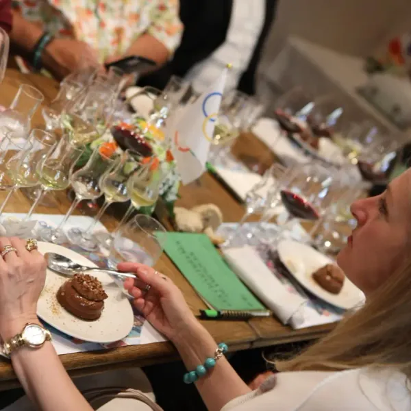 A woman tastes a dessert in front of a table with several wine glasses and small dishes.
