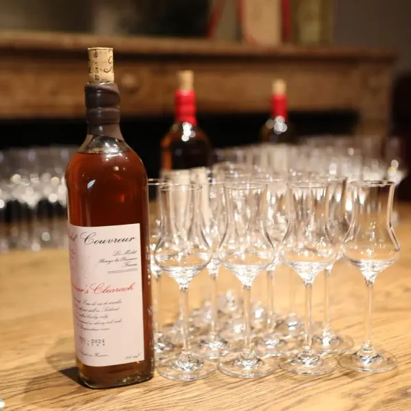 A bottle of whisky with tasting glasses lined up on a wooden table