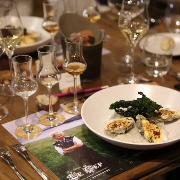Table set with wine glasses, plates containing oysters and side dishes, and promotional placemats