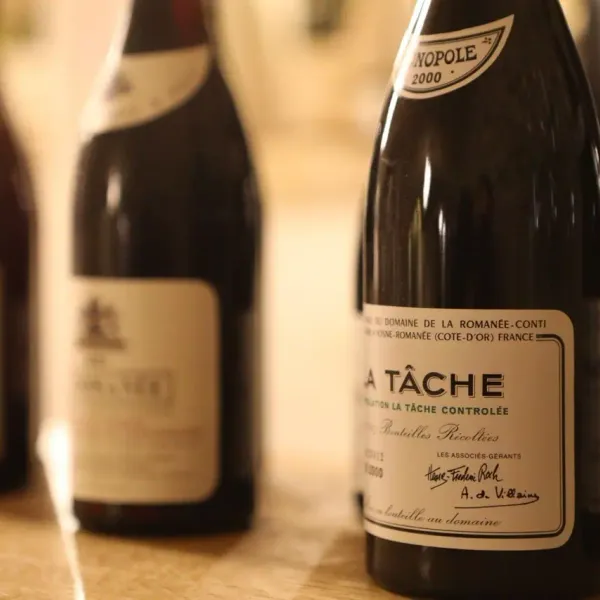 Bottles of La Tâche wine from the Domaine de la Romanée-Conti placed on a wooden table