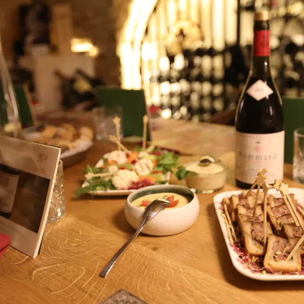 Table set with various dishes, a bottle of wine, and glasses, in a setting lit by dim lights.