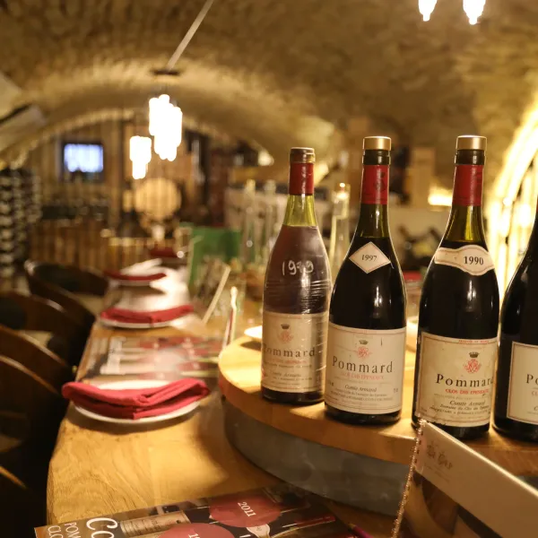 Bottles of wine lined up on wooden shelves with labels indicating different harvest years