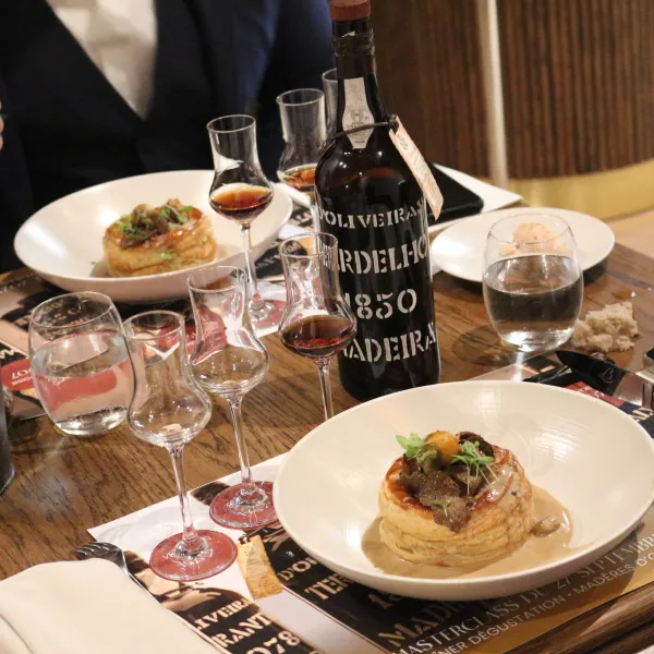 A table with wine glasses, a wine bottle, plates of food, and cutlery