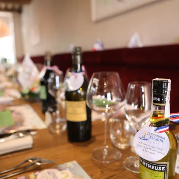 Bottle of Chartreuse and wine glasses on a table with brochures and menus