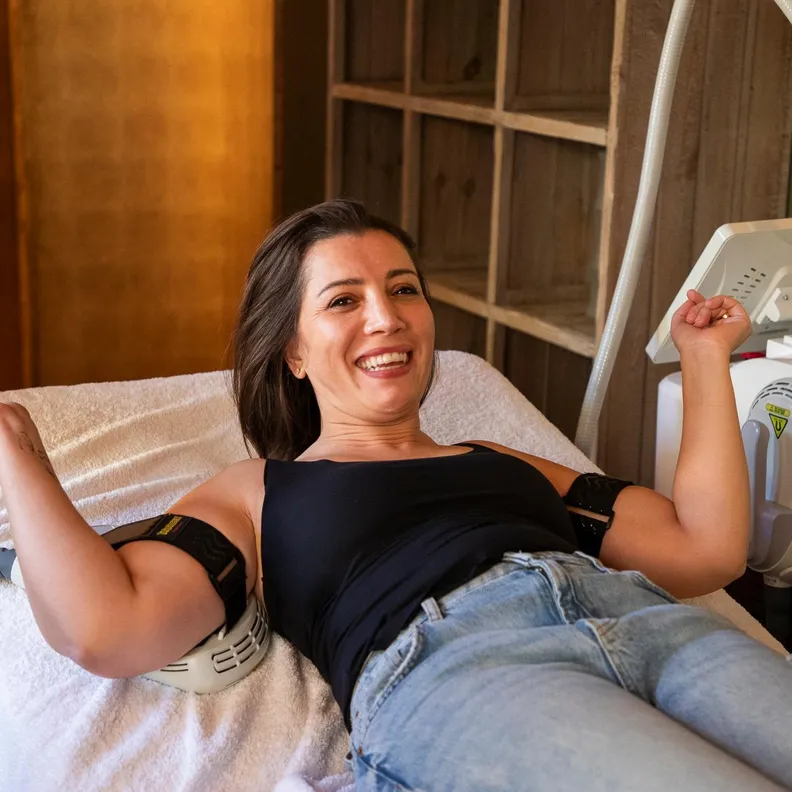 Smiling woman lying on a medical chair with an ultrasound device near her leg