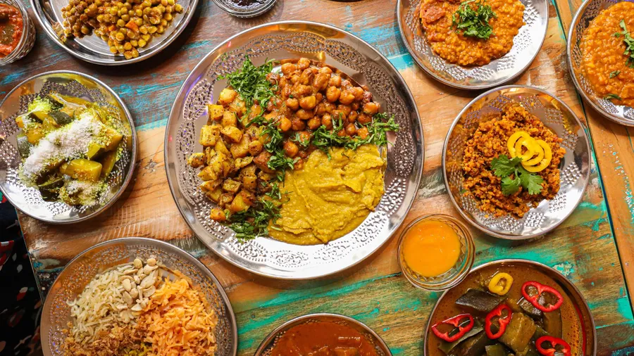 Un assortiment de plats indiens traditionnels disposés sur une table en bois coloré