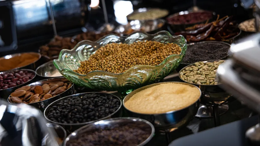 Different types of seeds and nuts arranged in metal and glass bowls on a counter