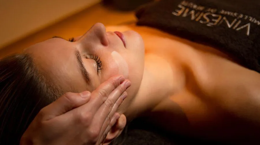 Une personne allongée reçoit un massage facial dans un cadre de spa